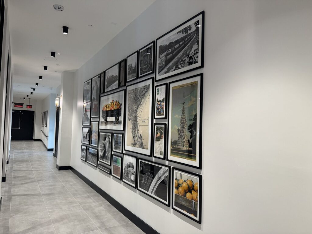 Large gallery wall of framed Florida history prints in a Kissimmee apartment clubhouse hallway