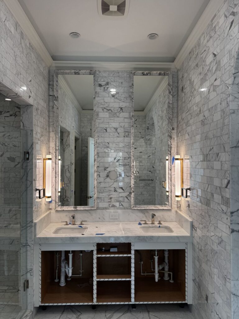 A matched pair of framed mirrors installed on marble tile above a double vanity