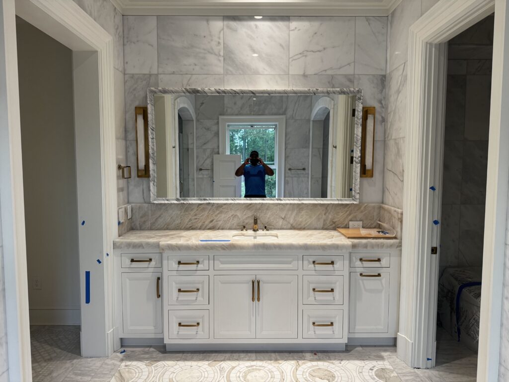 A 42 by 78 inch RH mirror, 119 pounds, installed onto marble tile above the backsplash