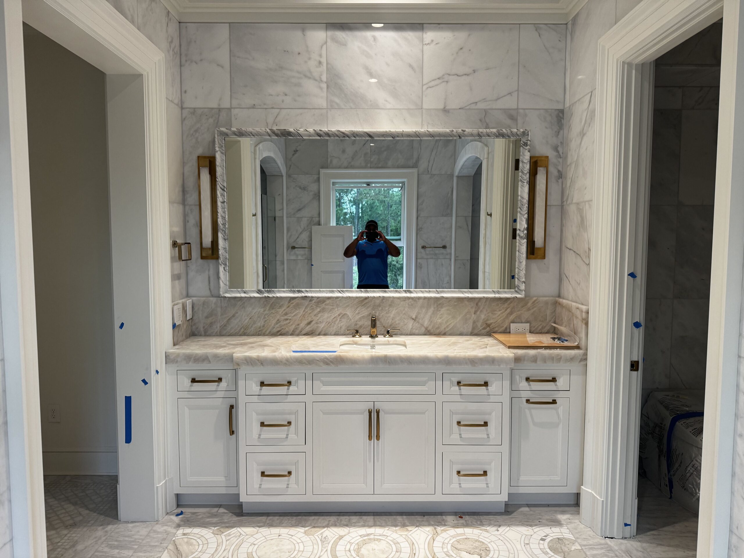 A 42 by 78 inch RH mirror, 119 pounds, installed onto marble tile above the backsplash